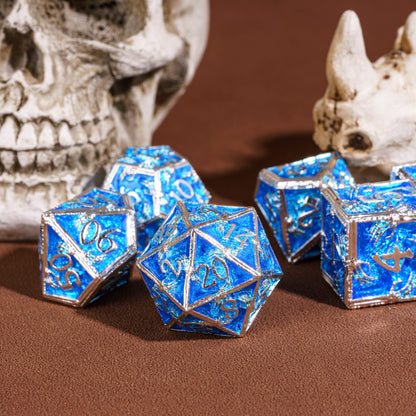 Frosted Crypt Metal Dice Set shimmering blue and silver D20 with skull background