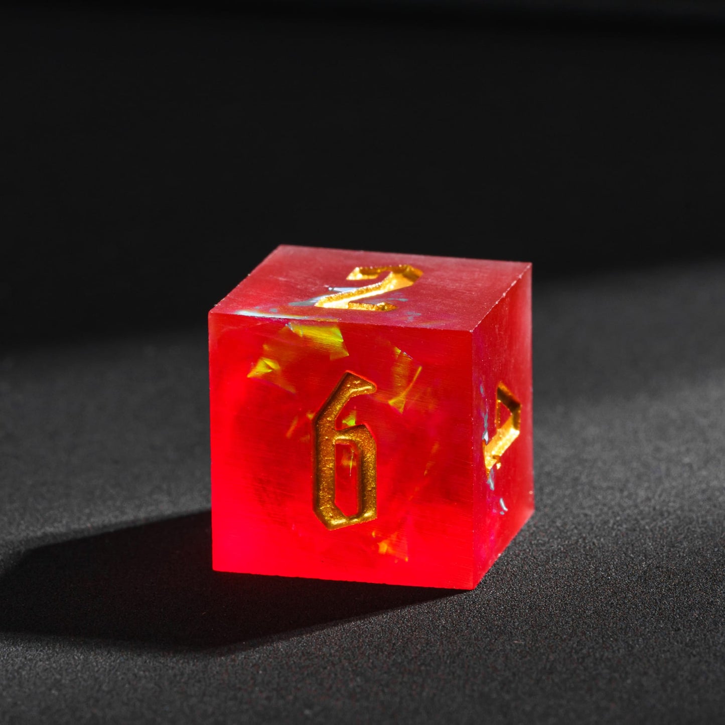 Frosted Ember sharp edge resin D6 with glowing ember inclusions and engraved gold numbering.