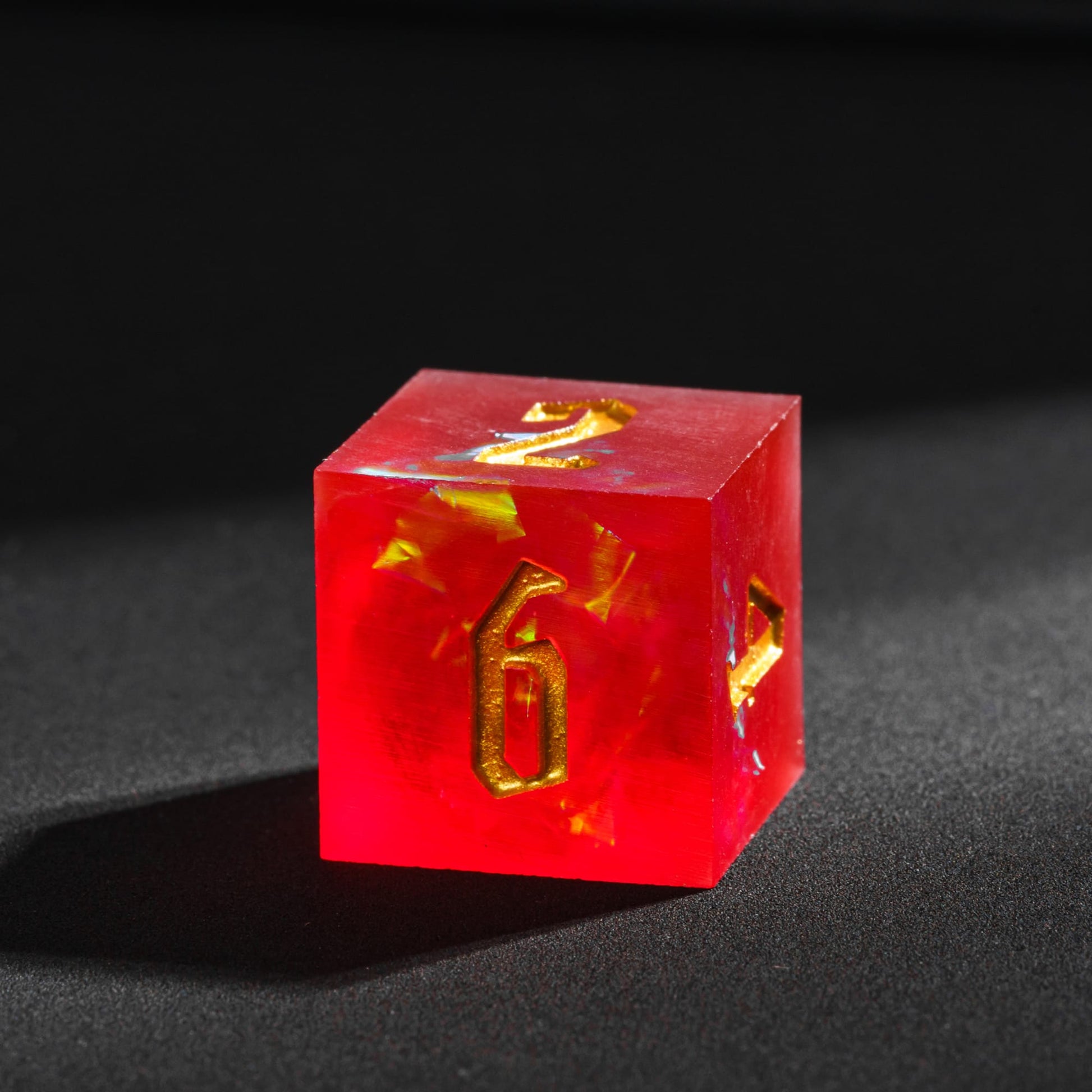 Frosted Ember sharp edge resin D6 with glowing ember inclusions and engraved gold numbering.