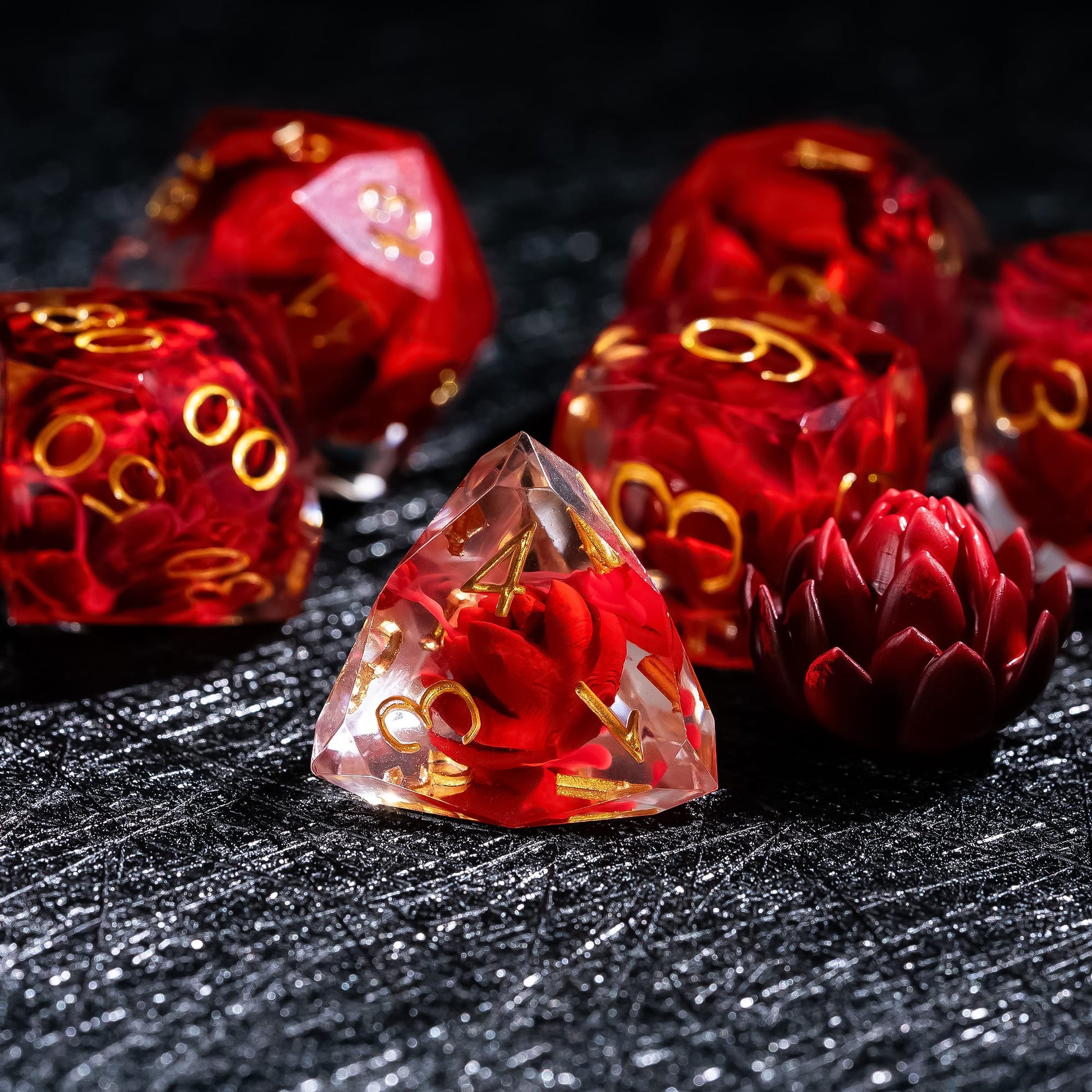 Infernal Lotus Sharp Edge Dice Set D4 close-up featuring a crimson lotus flower embedded in clear red resin with gold numbering