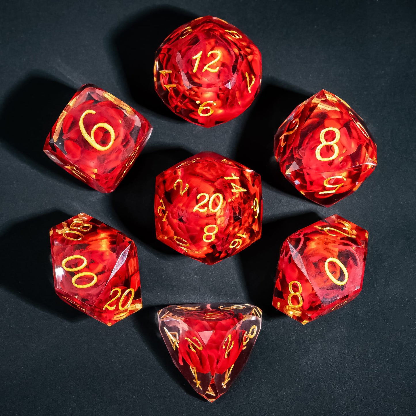 Infernal Lotus Sharp Edge Dice Set flat lay featuring crimson lotus flower inclusions suspended in translucent red resin with gold numbering