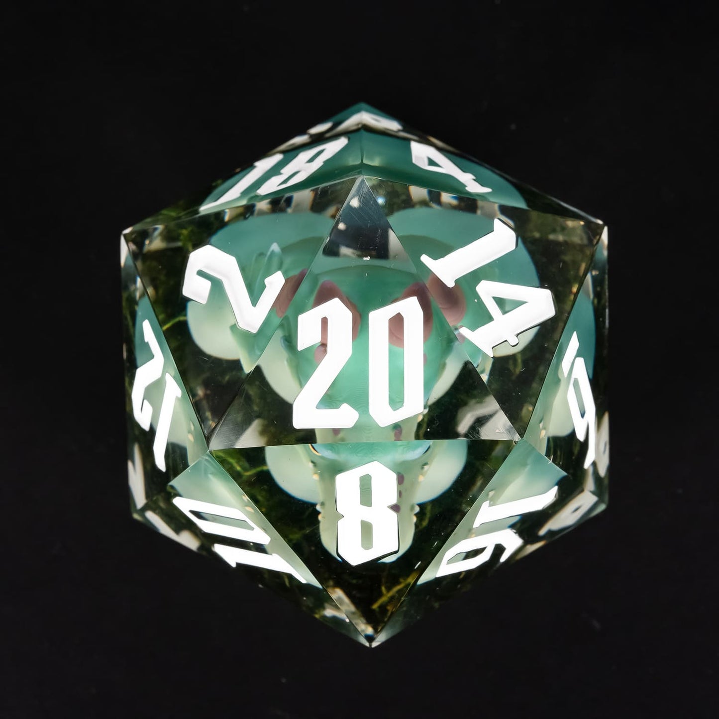 Top view of oversized green kobold D20 with embedded miniature