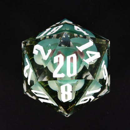 Top view of oversized green kobold D20 with embedded miniature