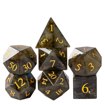 Labradorite Essence stone dice set crafted from natural labradorite gemstone with smoky gray tones, shimmering flashes of color, and gold numbering, perfect for tabletop RPGs.