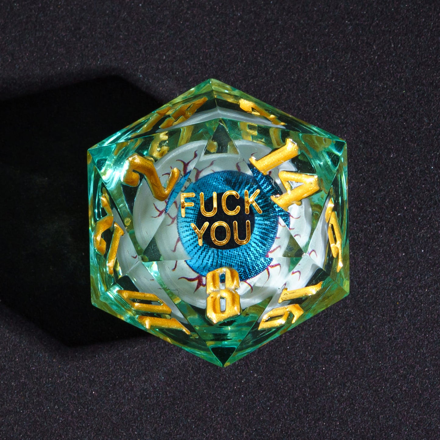 Close up of Liquid Core Eye Blue Fuck You D20 Sharp Edge Die with gold numbers for DnD