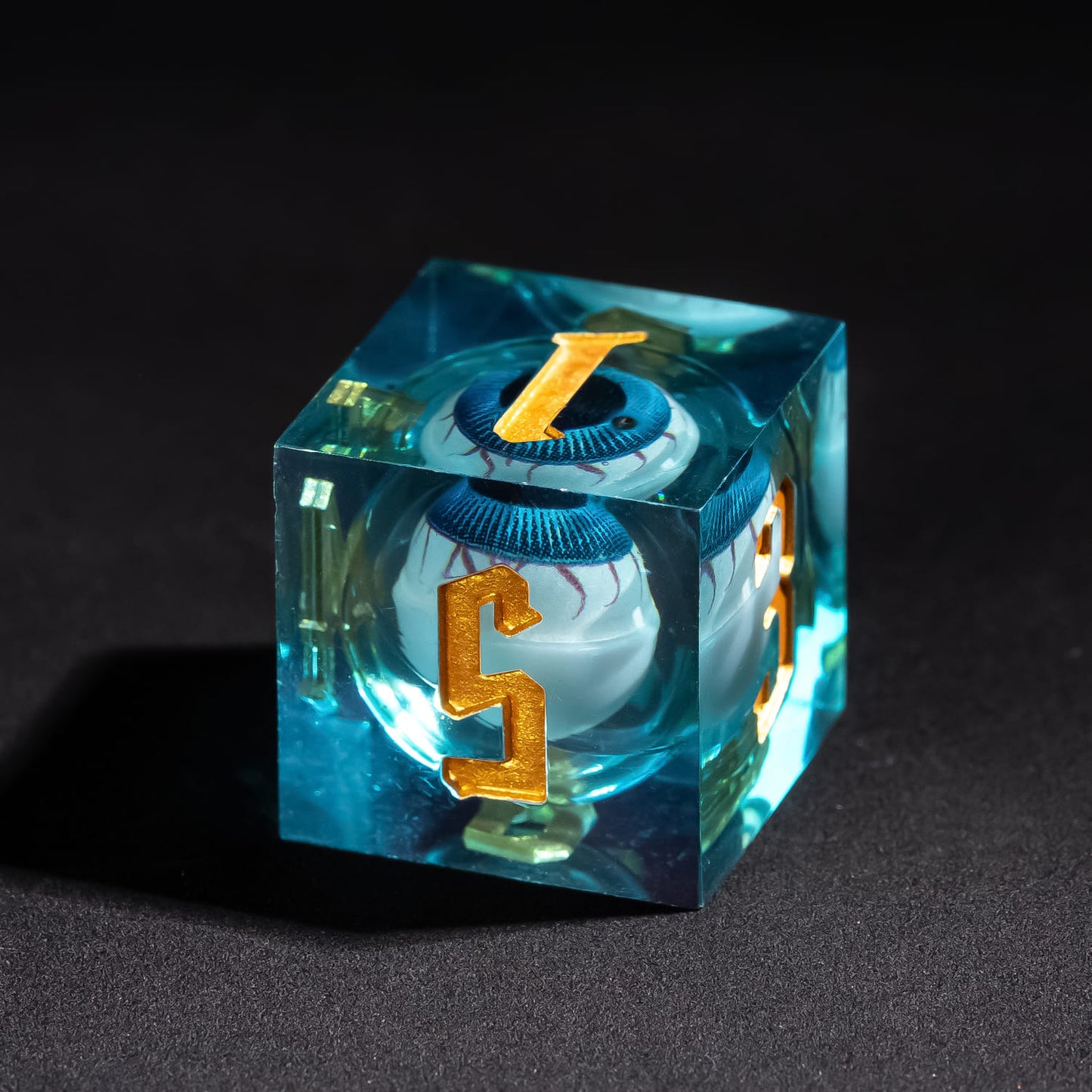 Close up of Liquid Core Eye Blue Sharp Edge D6 showing floating blue liquid eye core and gold numbering
