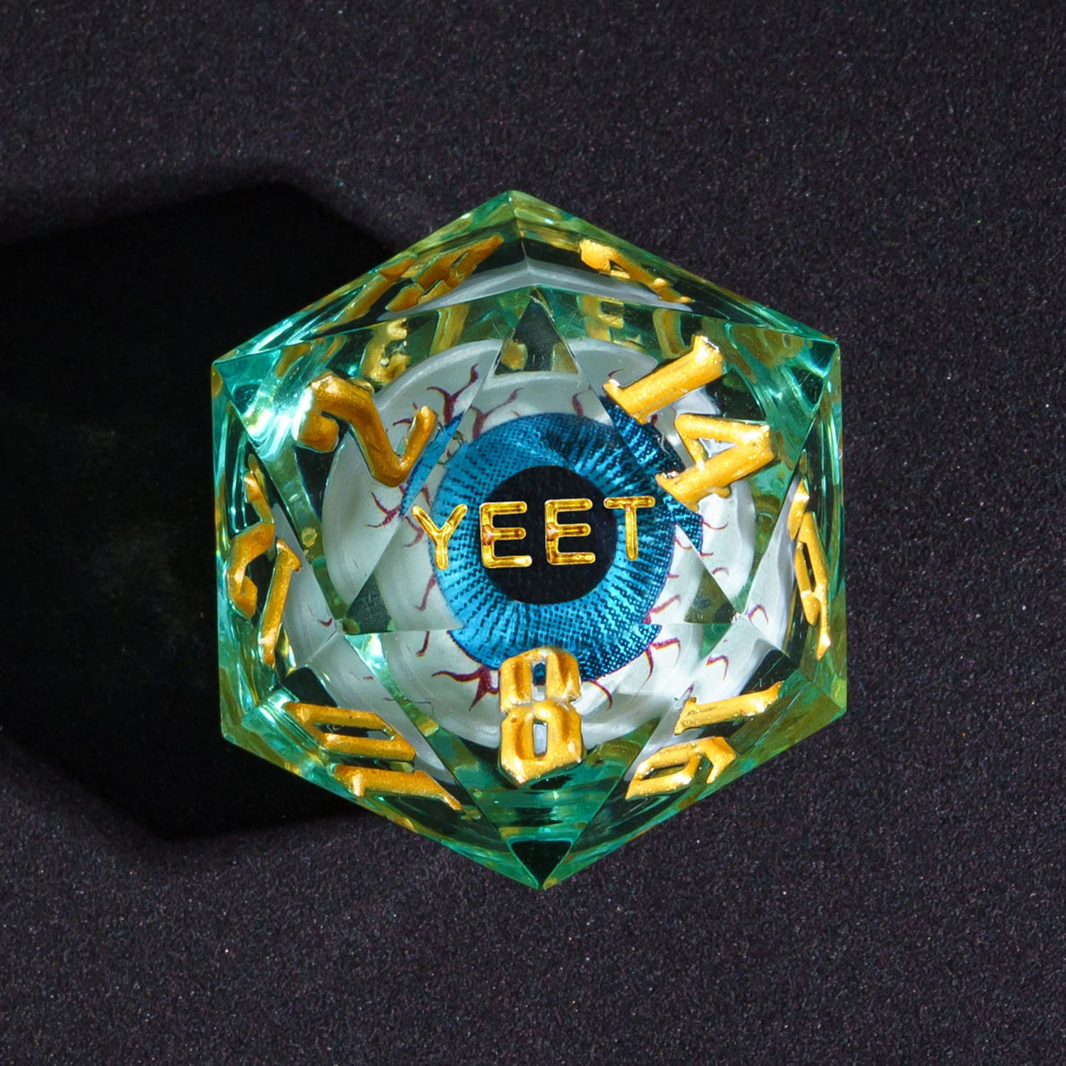 Close up of Liquid Core Eye Blue Yeet D20 Sharp Edge Die with gold numbering for DnD