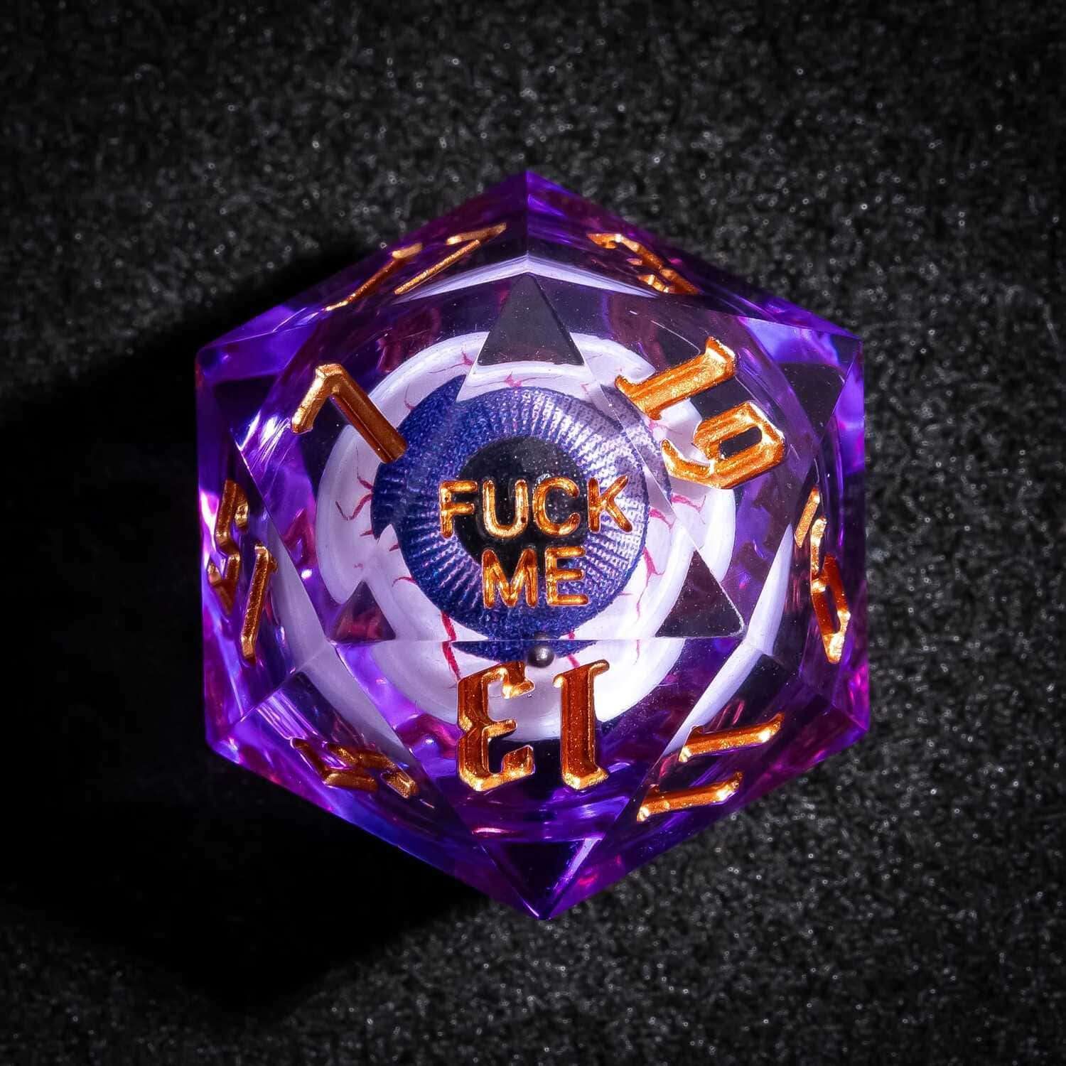 Close up of purple Liquid Core Eyeball D20 with gold numbers and Fuck Me face for tabletop RPGs