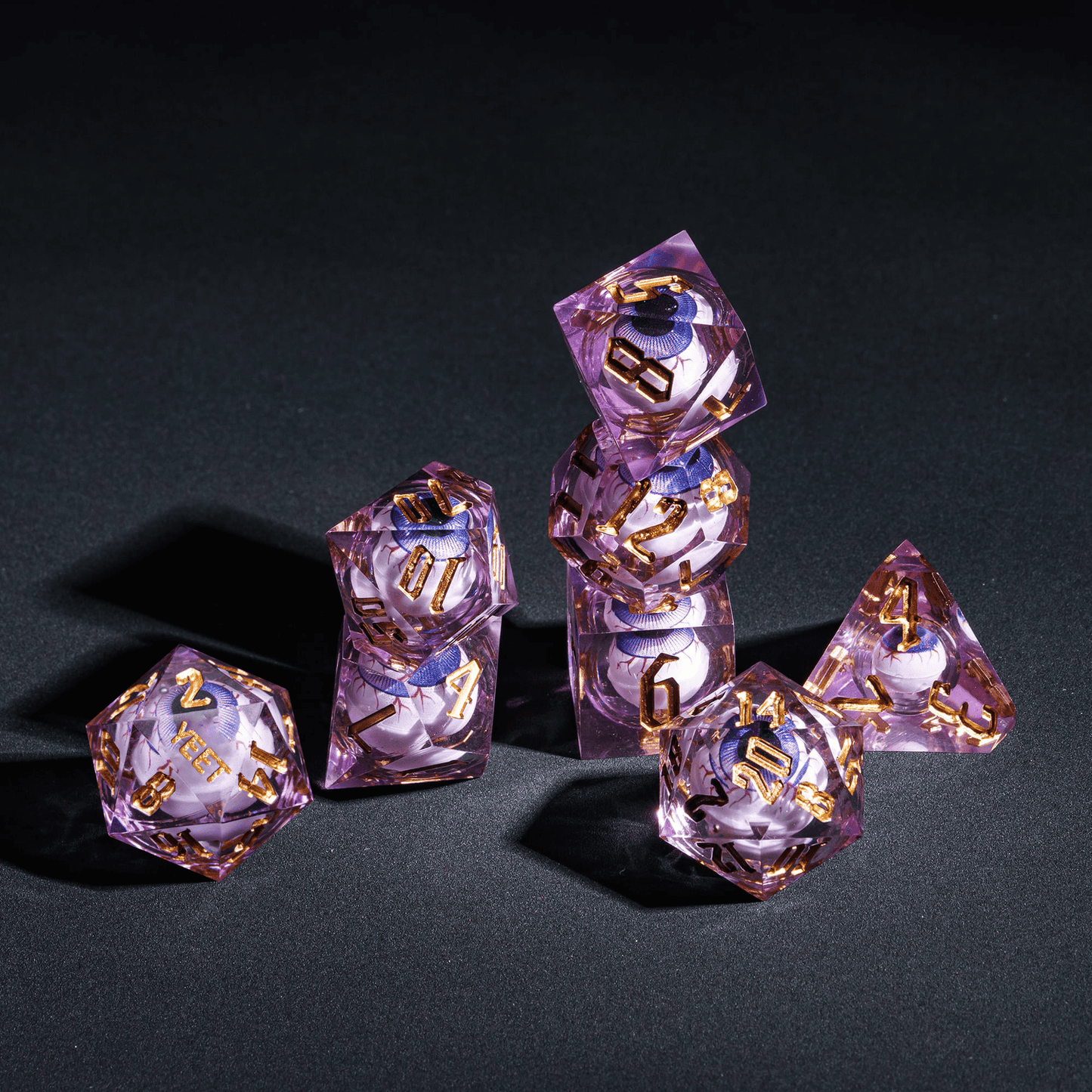 Stacked display of purple Liquid Core Eyeball Yeet Sharp Edge Dice Set with gold numbers for DnD & TTRPGs