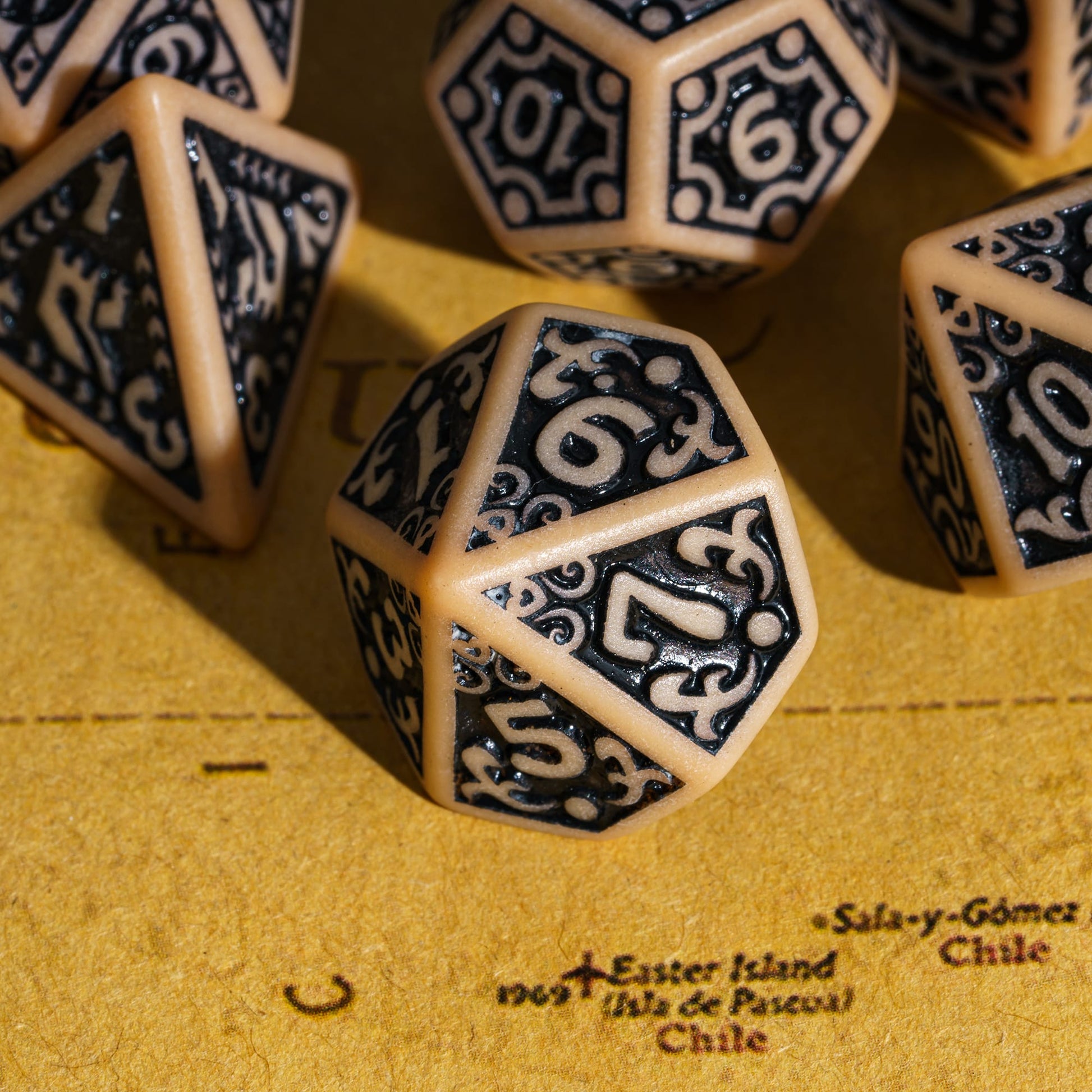 Close-up of brown Medieval Majesty d10 with black engravings, displayed on parchment