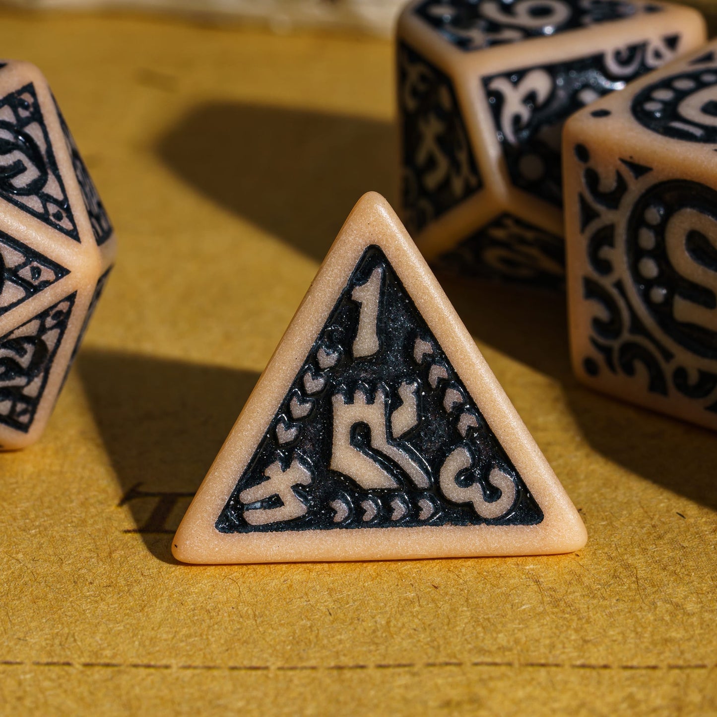 Close-up of brown Medieval Majesty d4 with black engravings, displayed on parchment