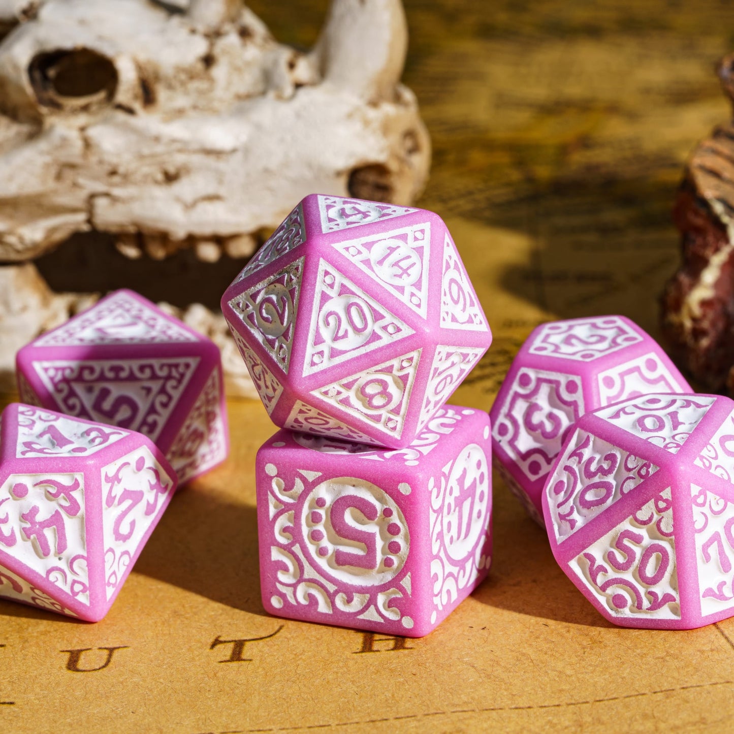 Pink Medieval Majesty dice scattered on a tabletop with ornate white detailing