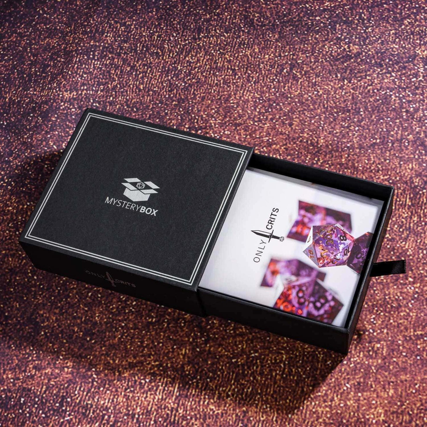 Only Crits Mystery Box with metal dice and purple backdrop for subscription display