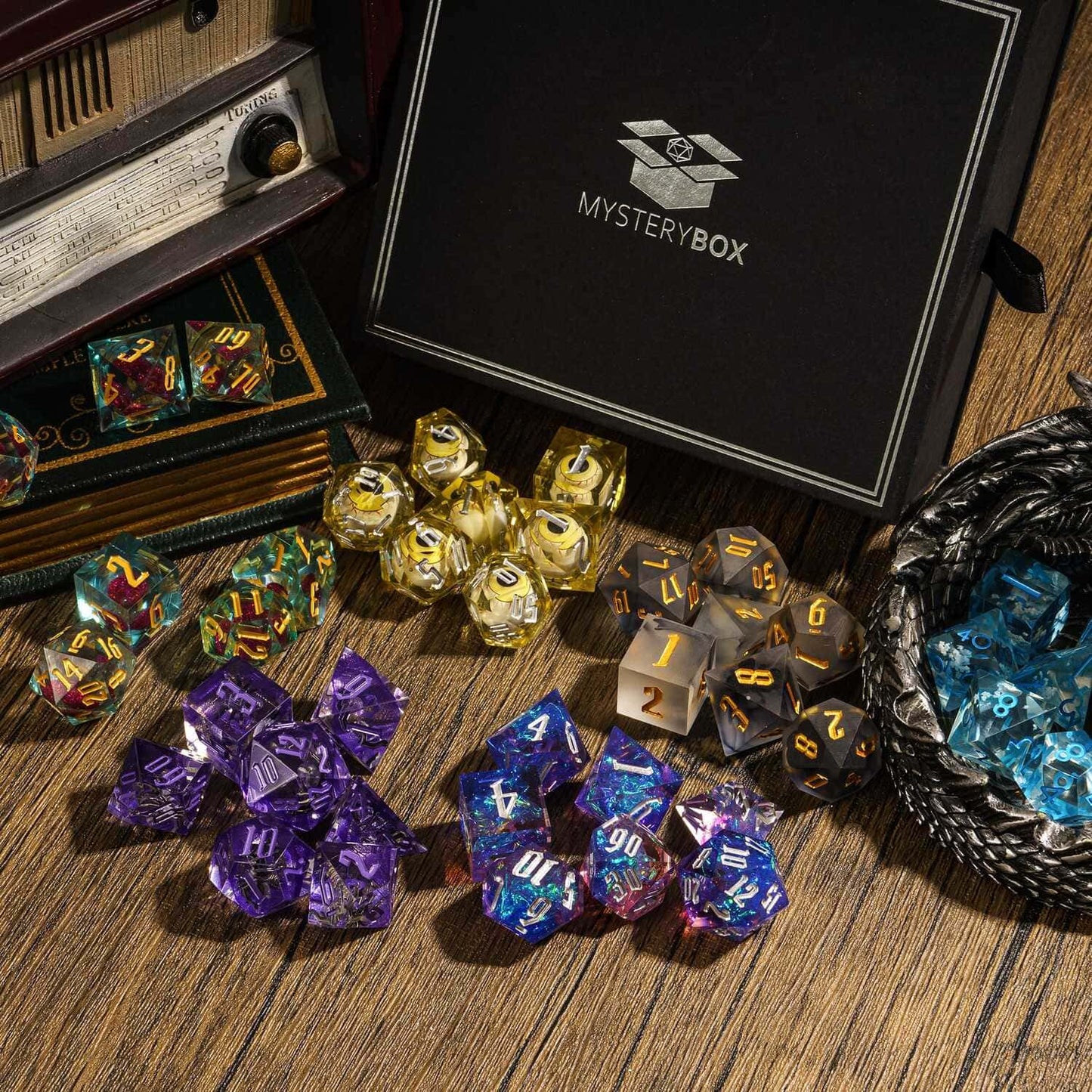 Assorted sharp edge dice sets around Only Crits Mystery Box on wooden surface