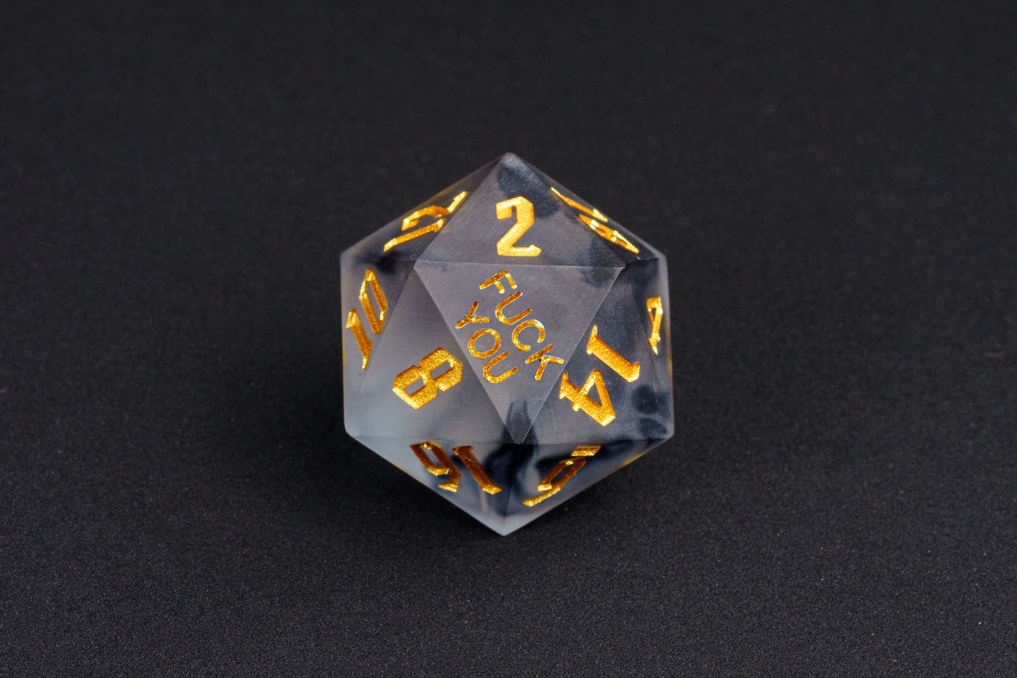 Close-up of Nimbus Noir F*ck Me sharp edge D20 with black smoke resin and gold numbers