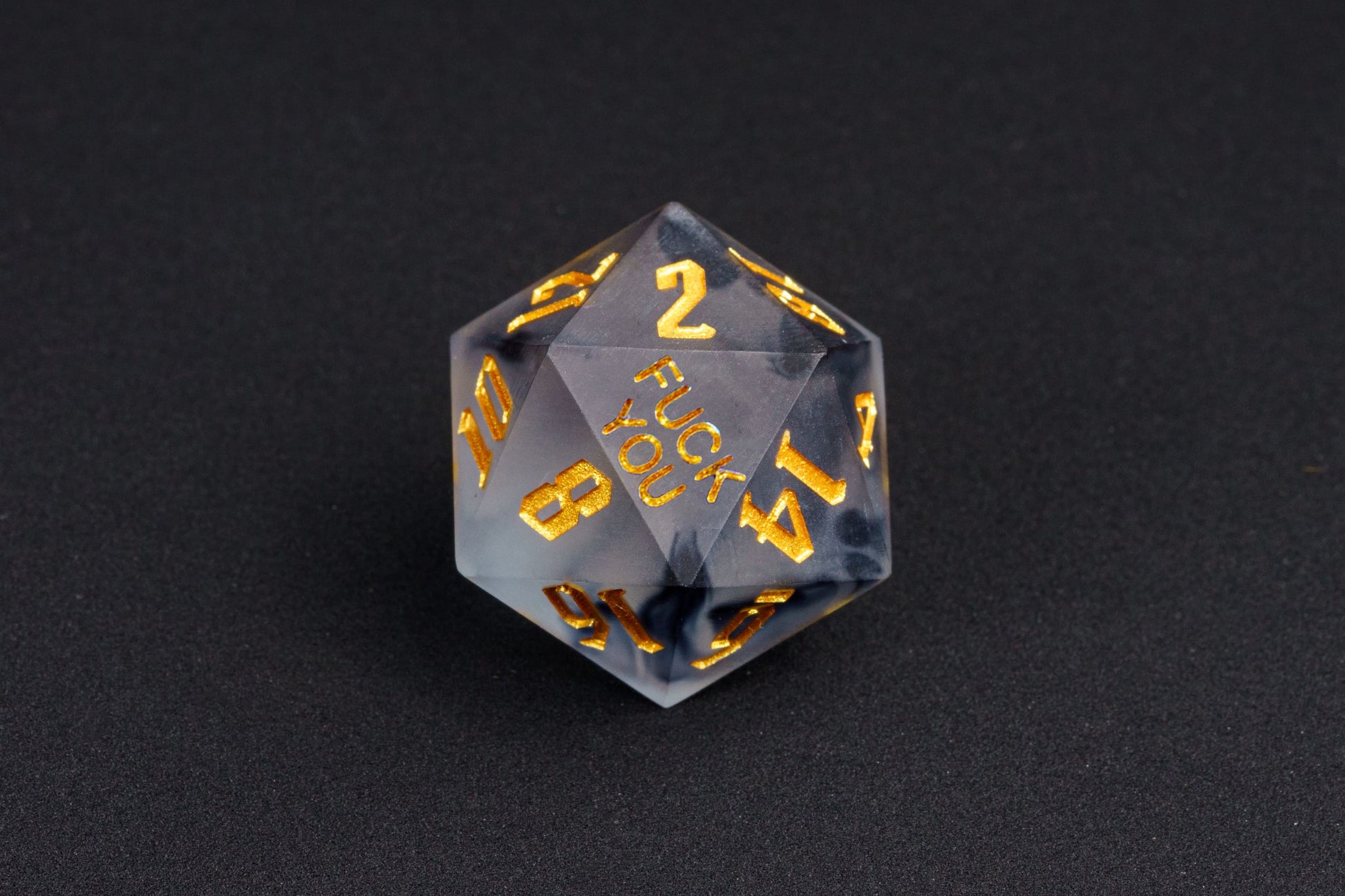 Close-up of Nimbus Noir F*ck Me sharp edge D20 with black smoke resin and gold numbers