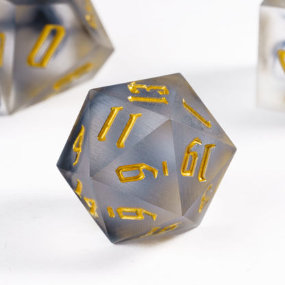 Closeup of Nimbus Noir Sharp Edge D20 die with smoky resin and gold numbers for DnD & DnD 5e