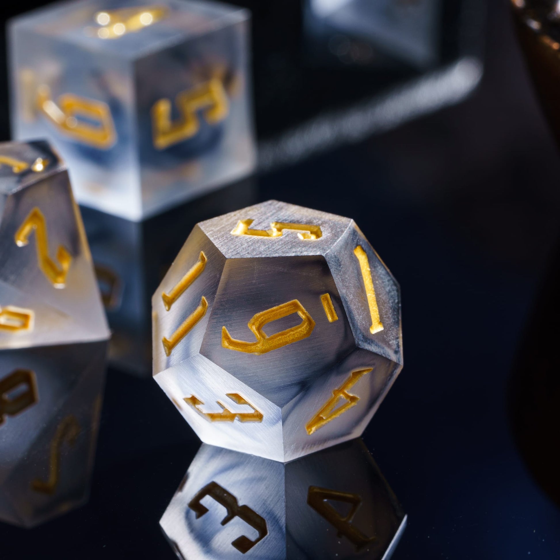 Dramatic closeup of Nimbus Noir Sharp Edge D20 die with smoky gray resin and gold numbering for DnD & DnD 5e