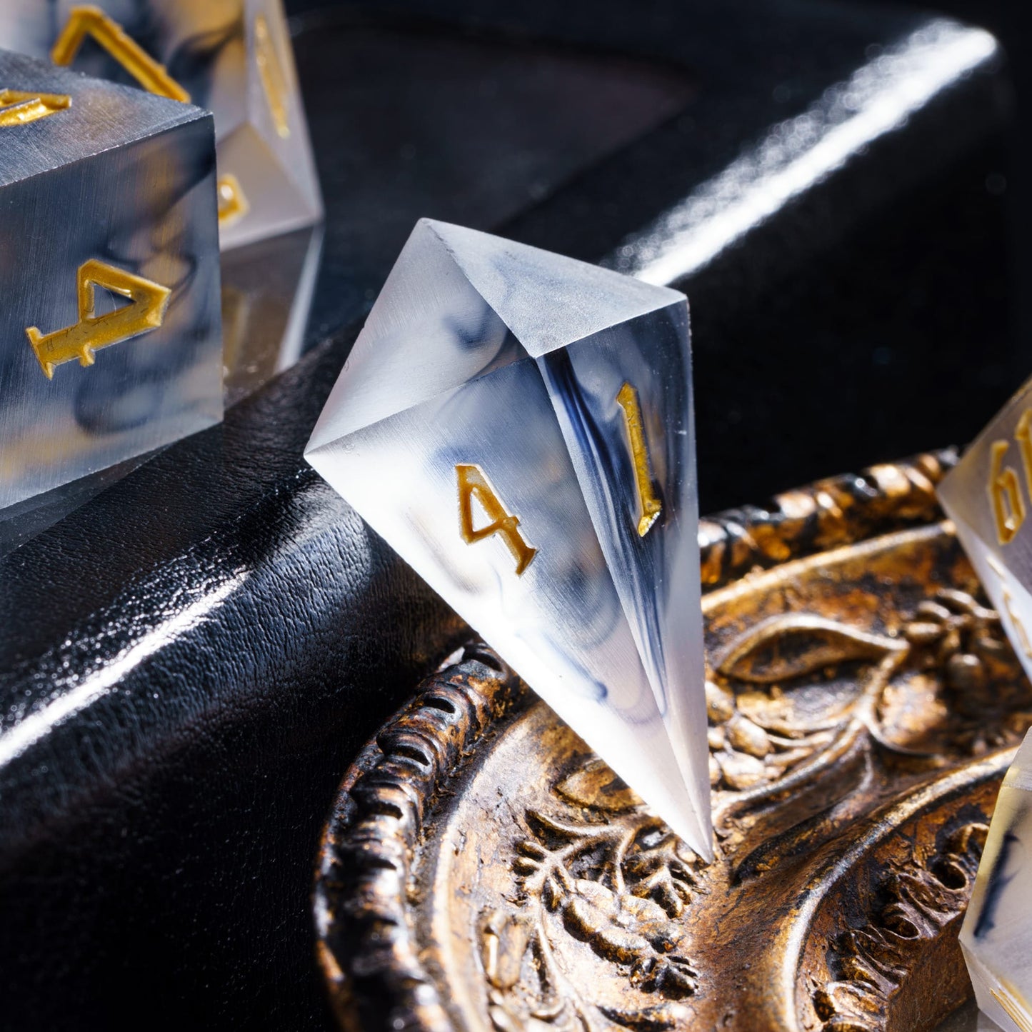 Nimbus Noir Sharp Edge D4 die placed on ornate tray with smoky resin and gold numbering for DnD & DnD 5e