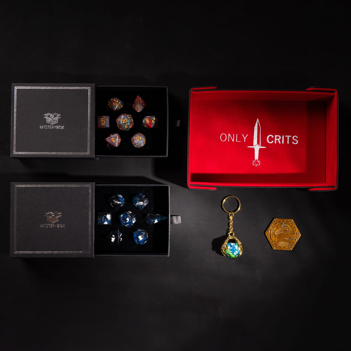 Deluxe Mystery Box example: two dice sets in mystery boxes with an Only Crits magnetic dice tray, keychain and coin
