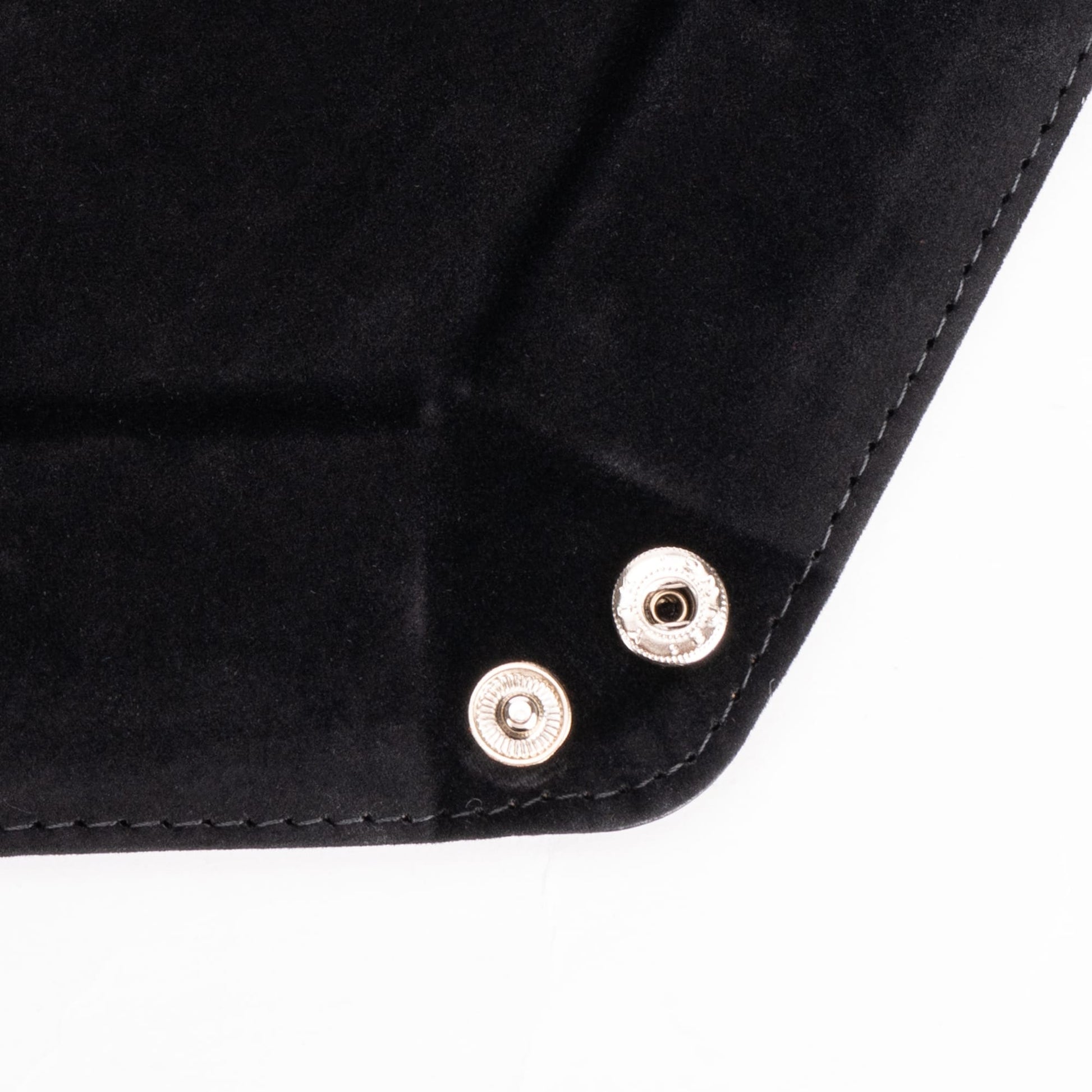 Close-up of metal snap buttons on black hexagon dice tray corner
