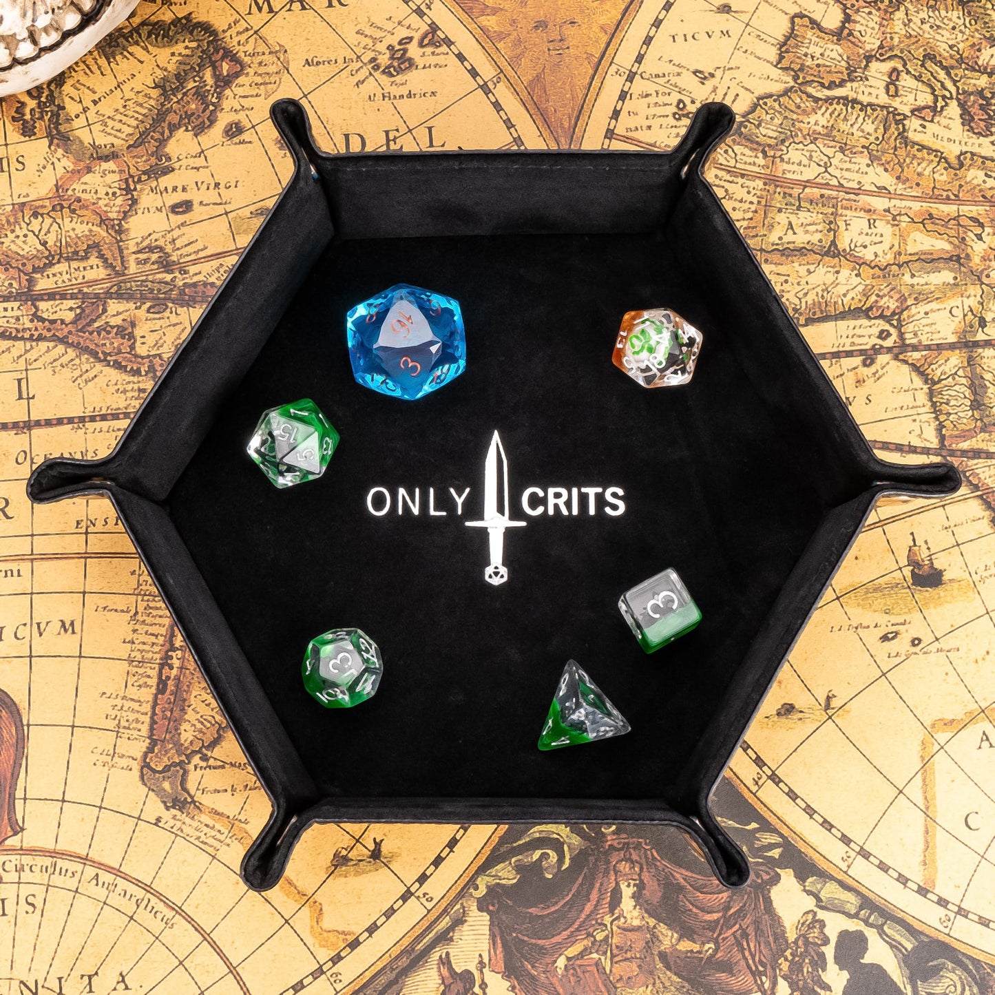 Black hexagon dice tray with Only Crits logo, top view with dice inside on fantasy map