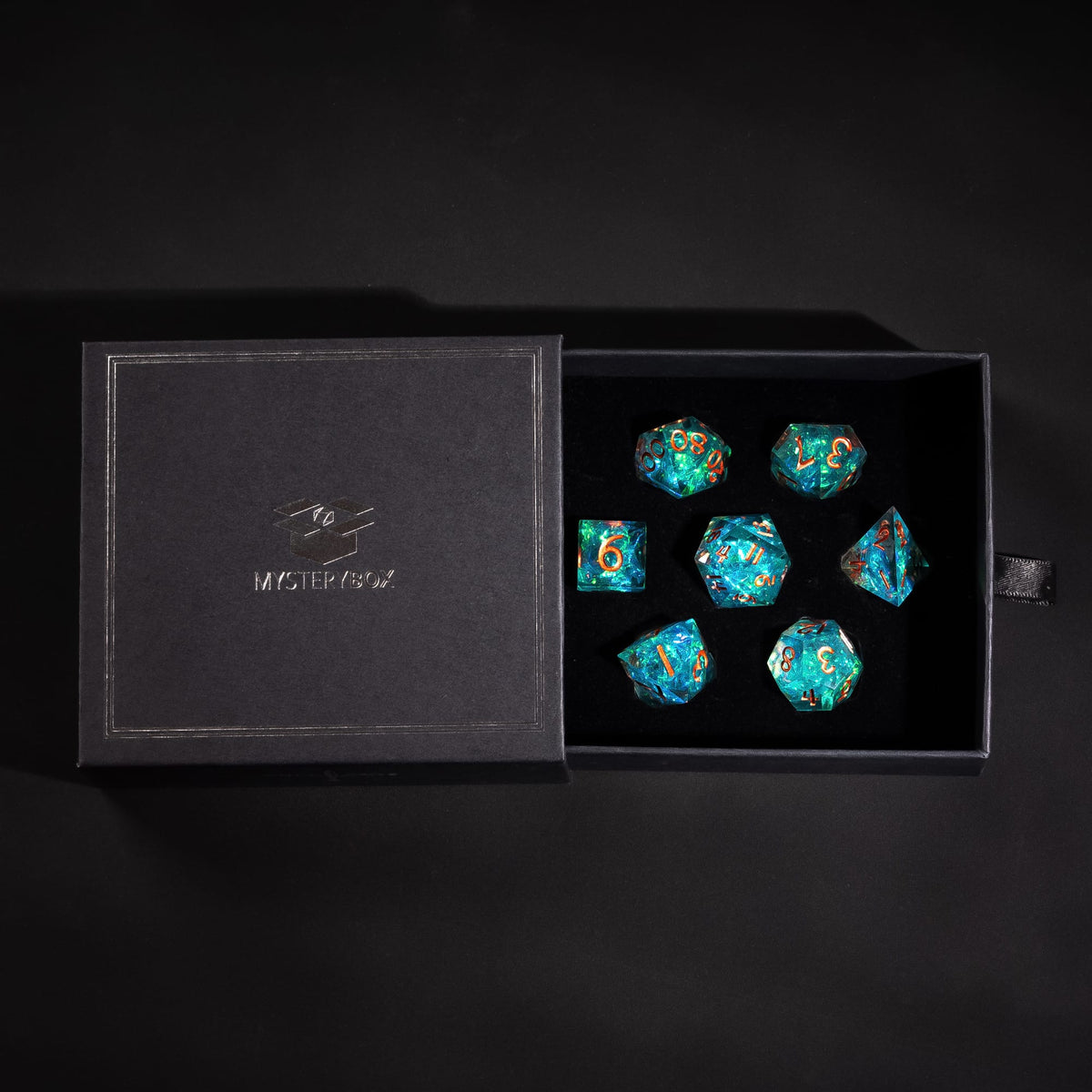 Premium Mystery Box open with a teal sharp edge dice set inside