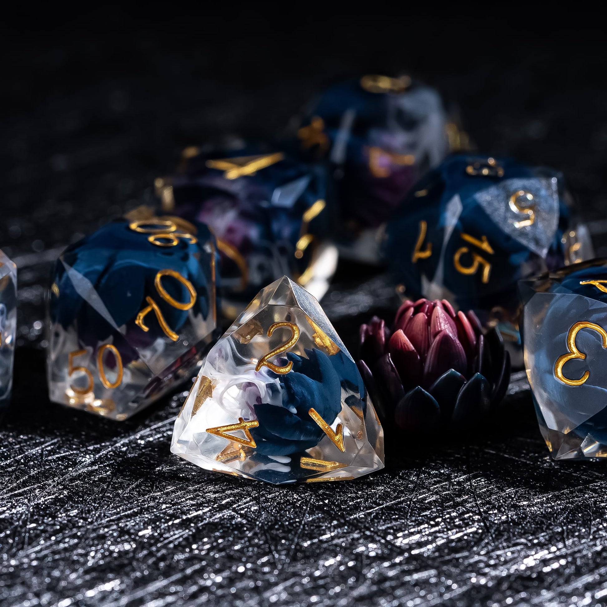 Phantom Lotus Sharp Edge Dice Set D4 close-up featuring a dark lotus flower encased in translucent resin with swirling white mist and gold numbering