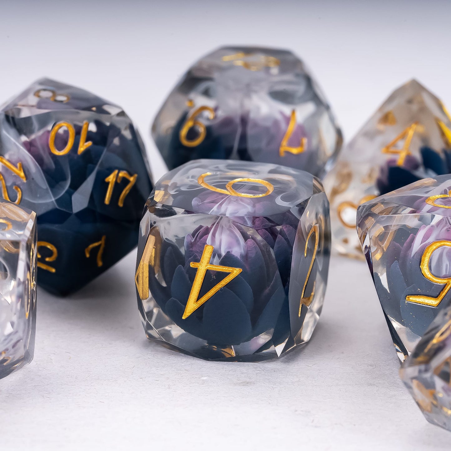 Phantom Lotus Sharp Edge Dice Set D6 close-up featuring a dark purple lotus flower suspended in smoky blue resin with gold numbering