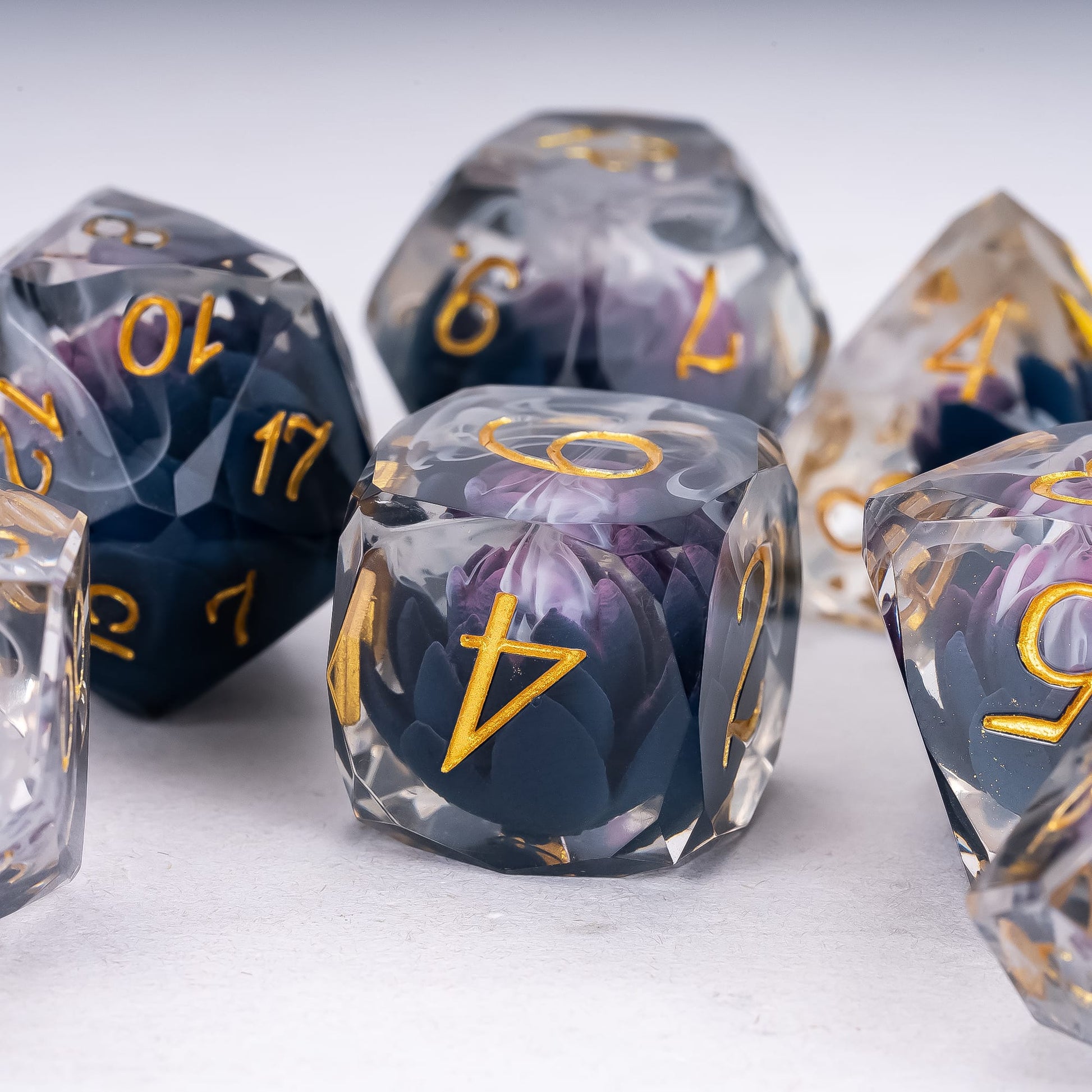 Phantom Lotus Sharp Edge Dice Set D6 close-up featuring a dark purple lotus flower suspended in smoky blue resin with gold numbering