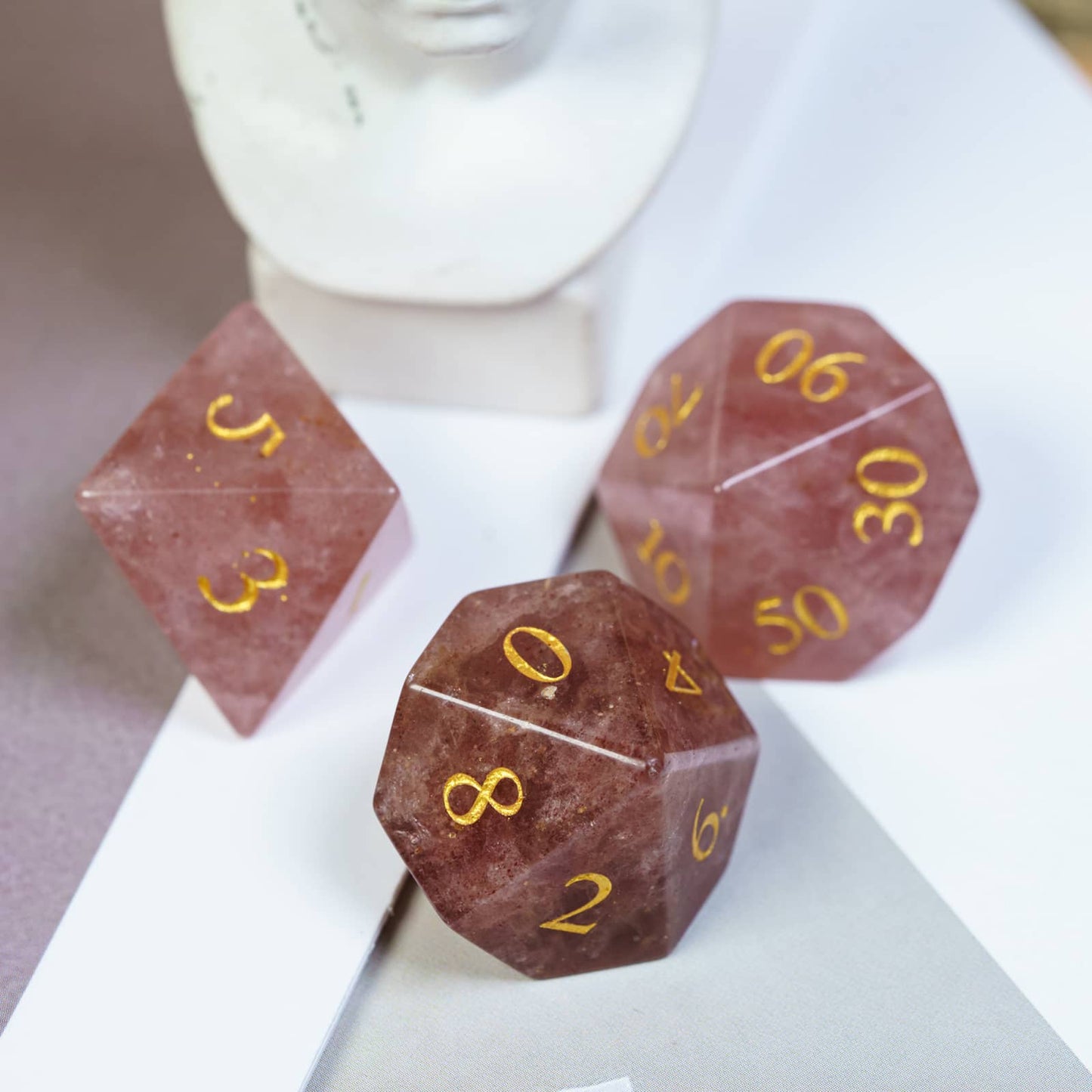 Close up of Rune Stone Sanguine Reverie d10 and D20 showing polished red stone and gold numbering for DnD