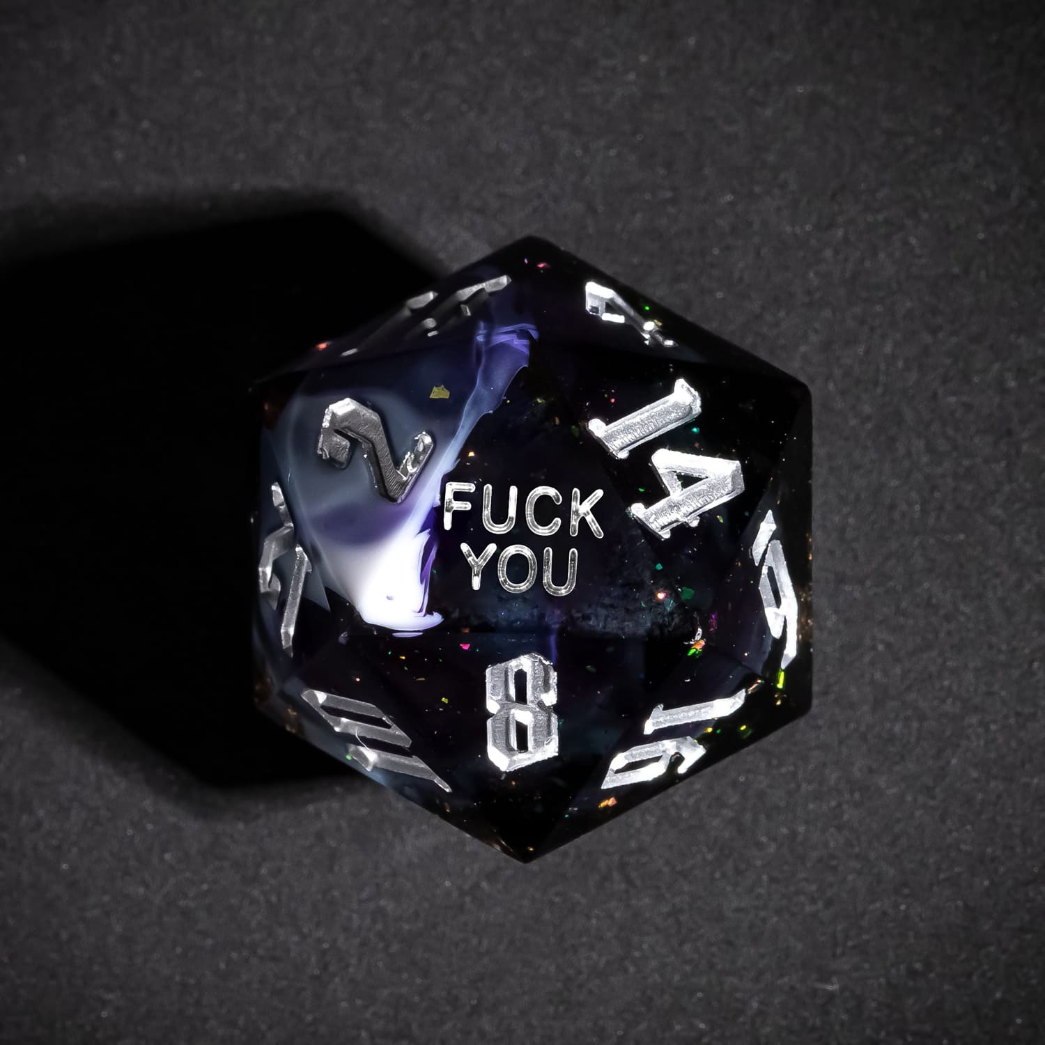 Close up of Siren's Cache Fuck You D20 with dark resin pattern and silver numbering
