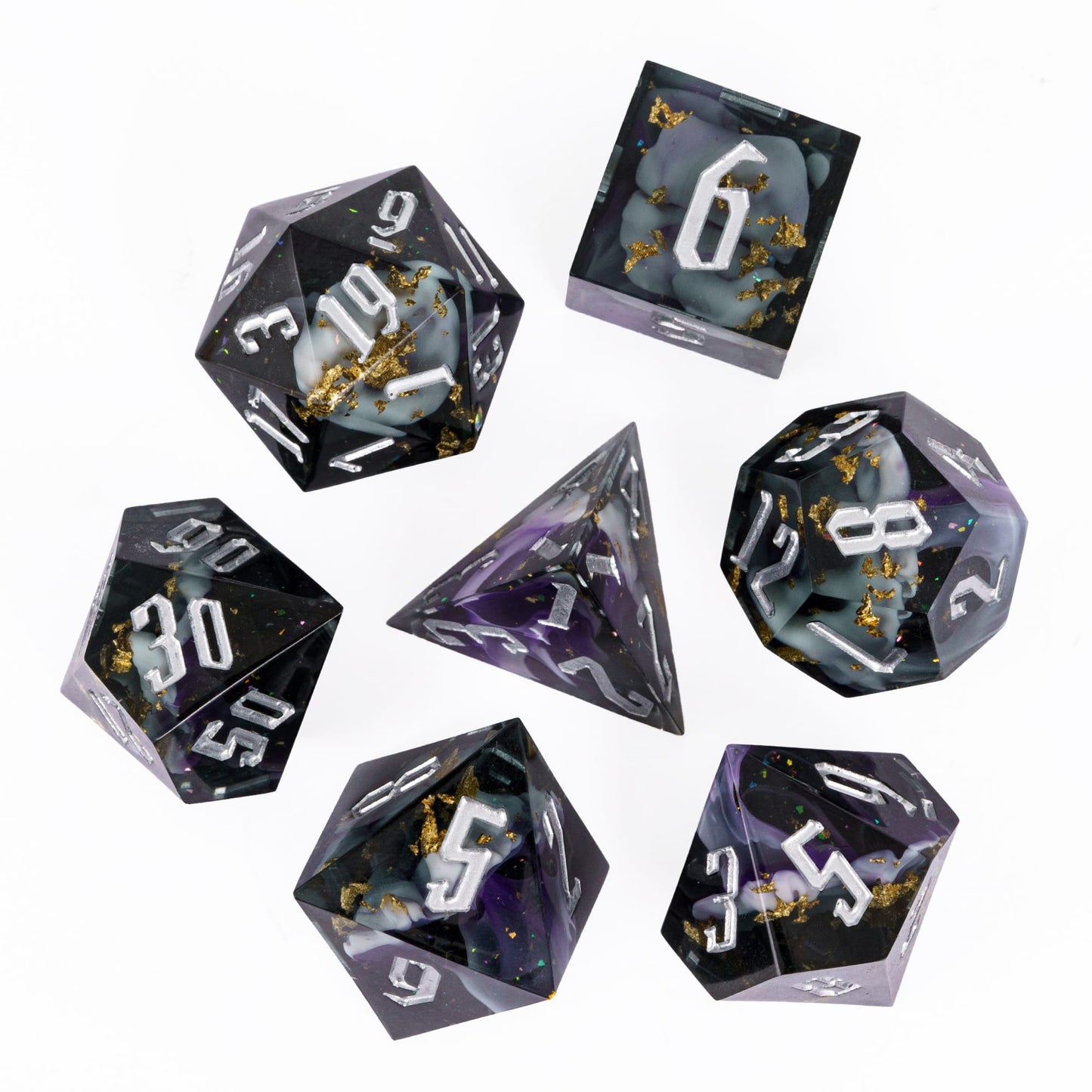 Flat lay of Siren’s Cache sharp edge resin dice set for DnD with silver numbers and gold foil detailing