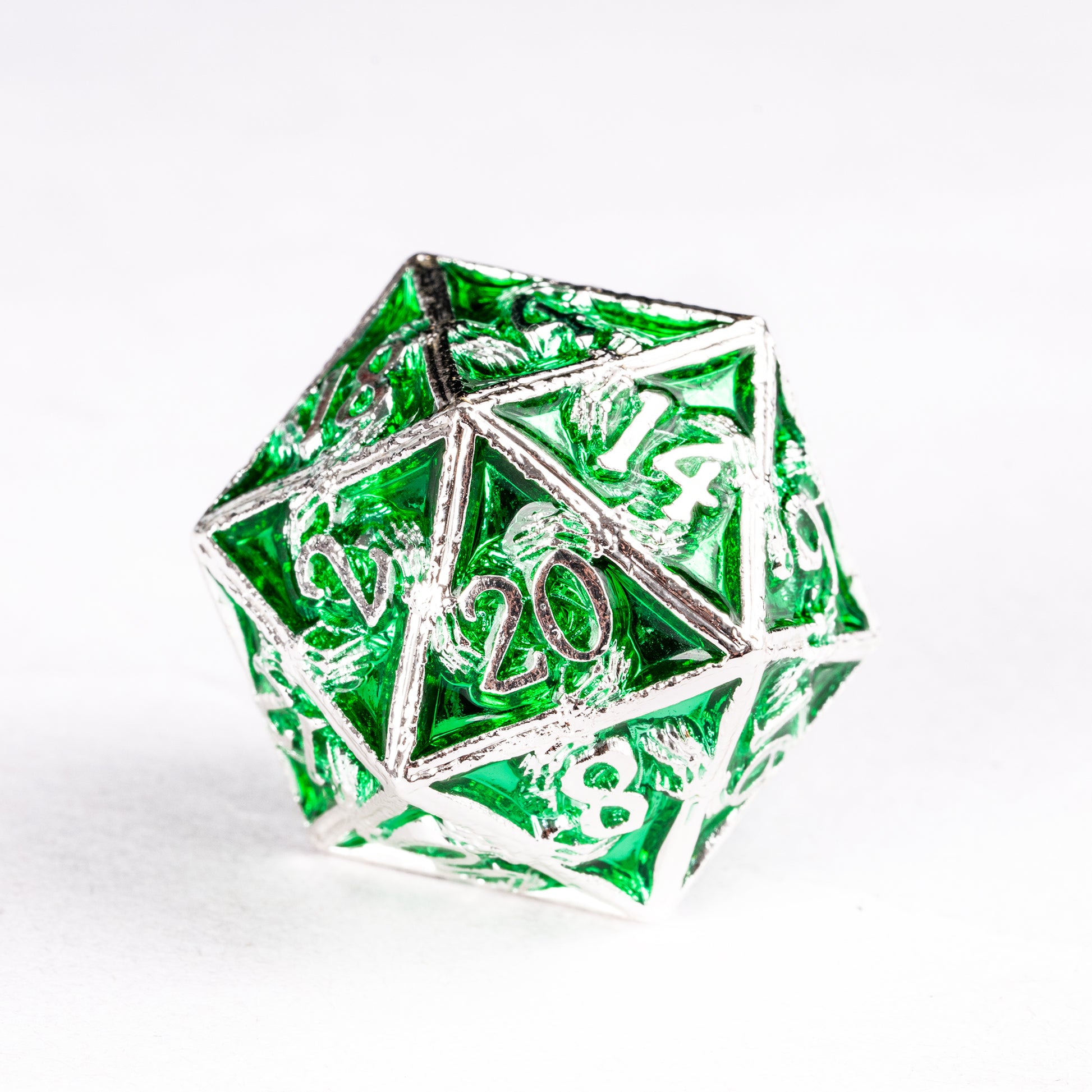 Close-up of Siren’s Crypt metal D20 featuring translucent emerald green panels framed in silver metal with engraved numbers.