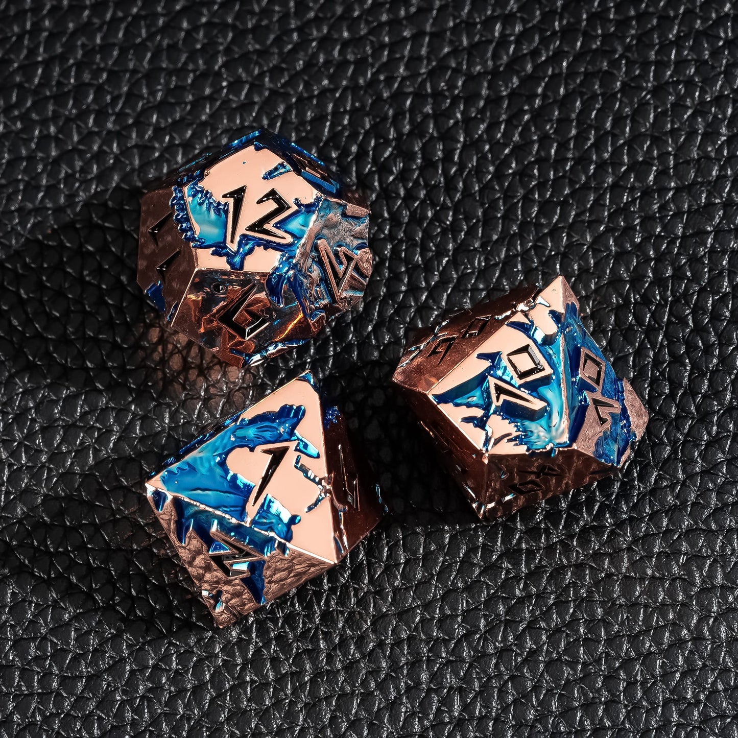 Close up of Stormwake Dragon metal dice showing blue inlay and engraved details