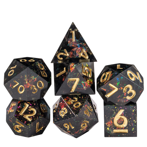 Stacked display of Supernova Remnant Sharp Edge 7 piece dice set with black resin, iridescent foil flakes, and gold numbering for DnD