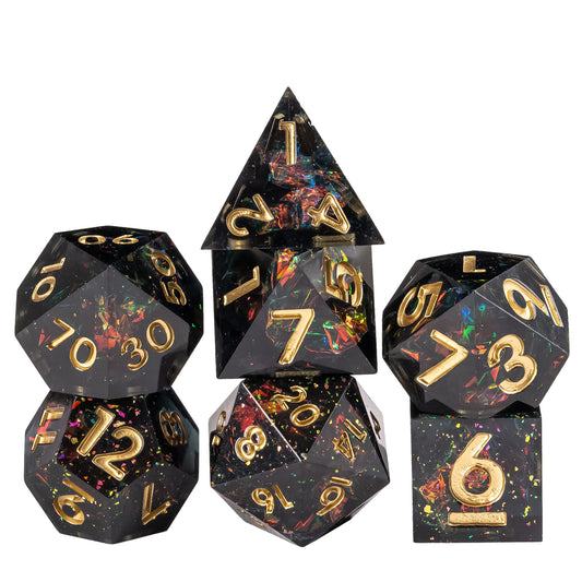 Stacked display of Supernova Remnant Sharp Edge 7 piece dice set with black resin, iridescent foil flakes, and gold numbering for DnD