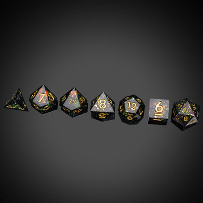 Supernova Remnant sharp edge dice set with black resin and gold numbers on dark background
