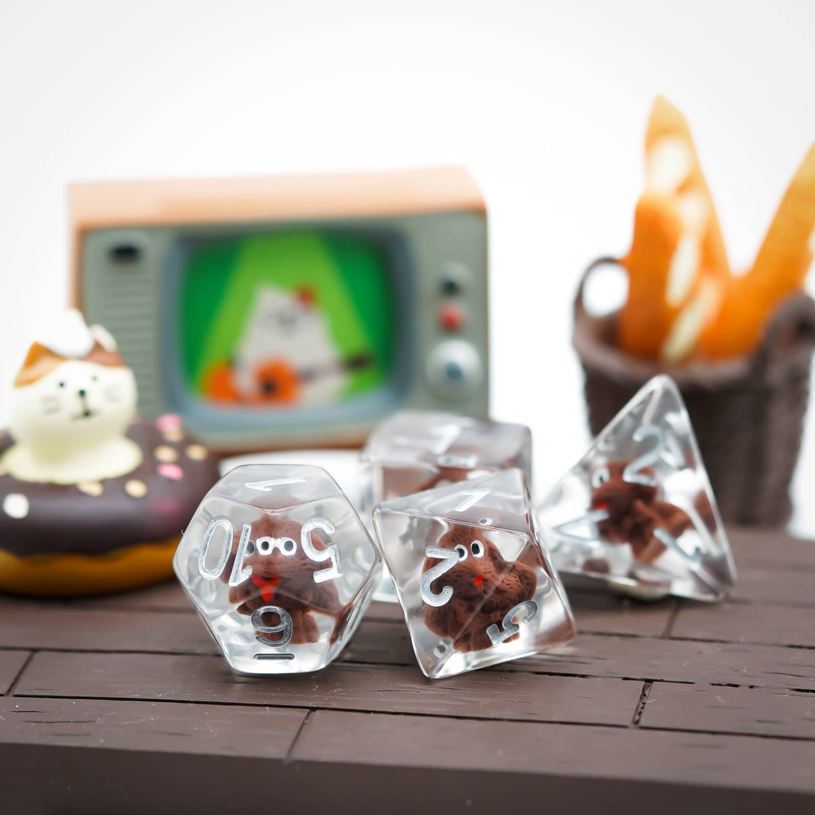 Transparent Doggo Dice Set on wooden table beside mini TV and donut cat figurine