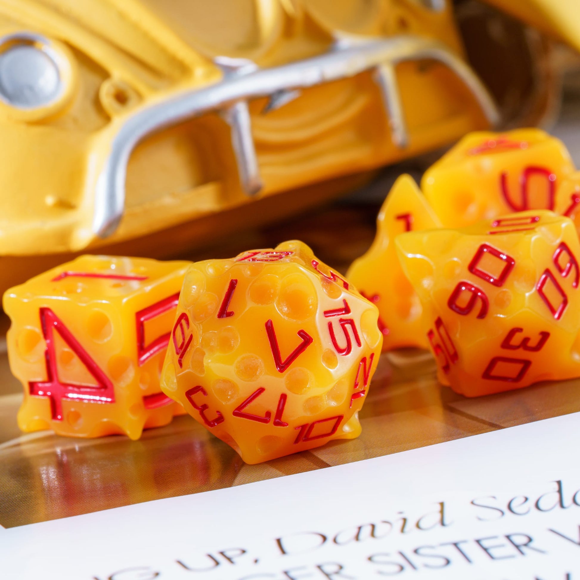Closeup of yellow Cheese Dice Set with red numbering for tabletop gaming