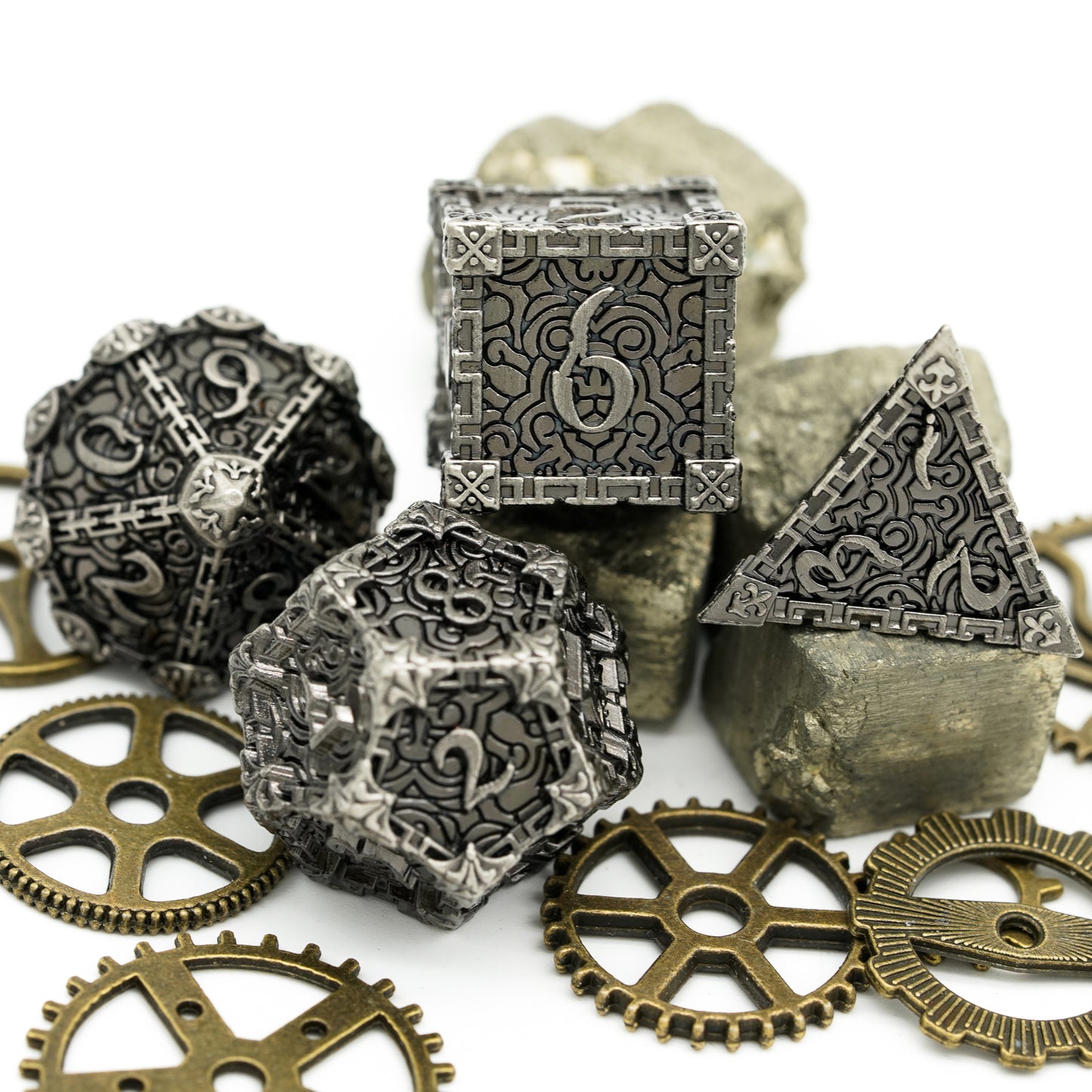 4 metal dice, stone color, displayed on gears and rocks