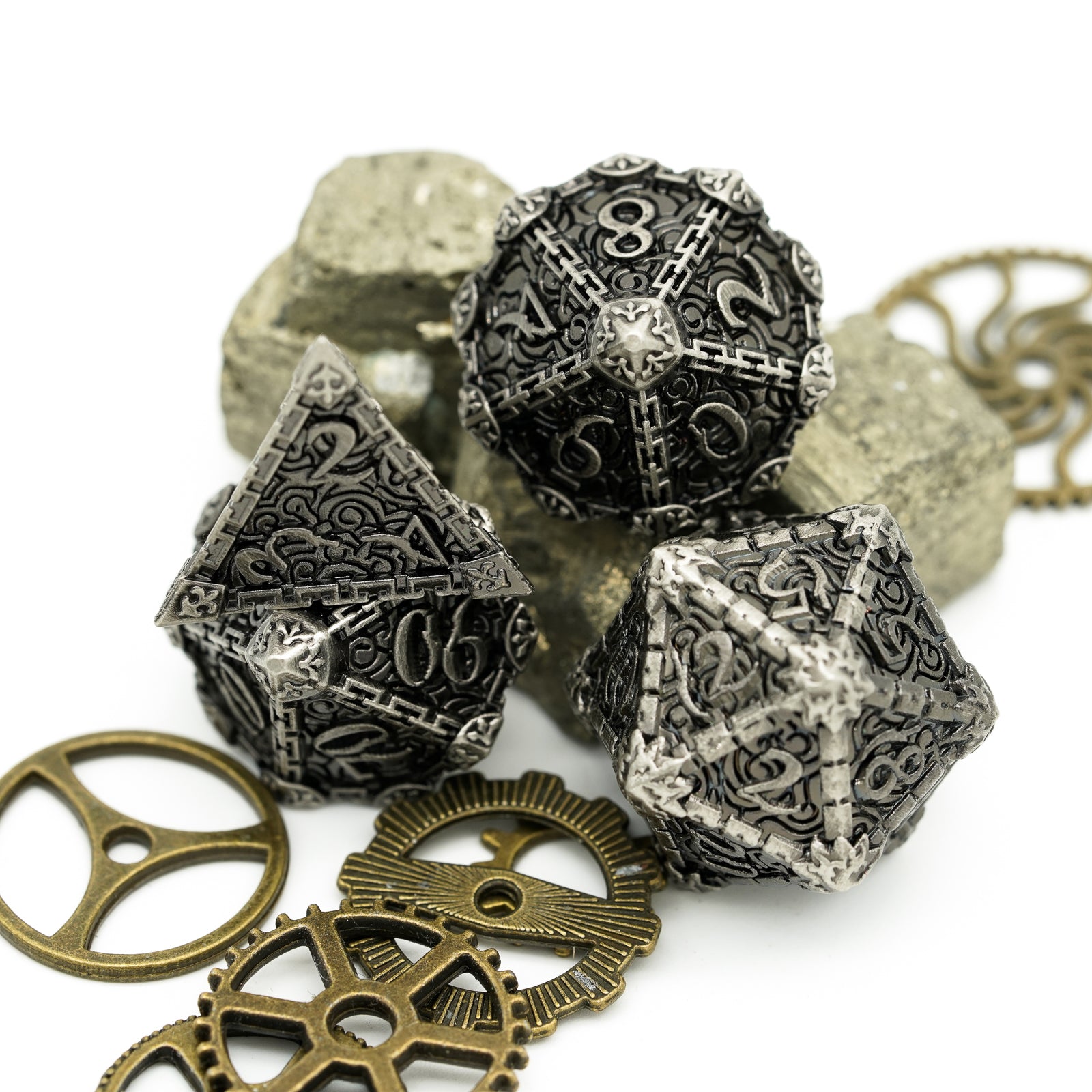 4 stone colored metal dice displayed on gears and rocks