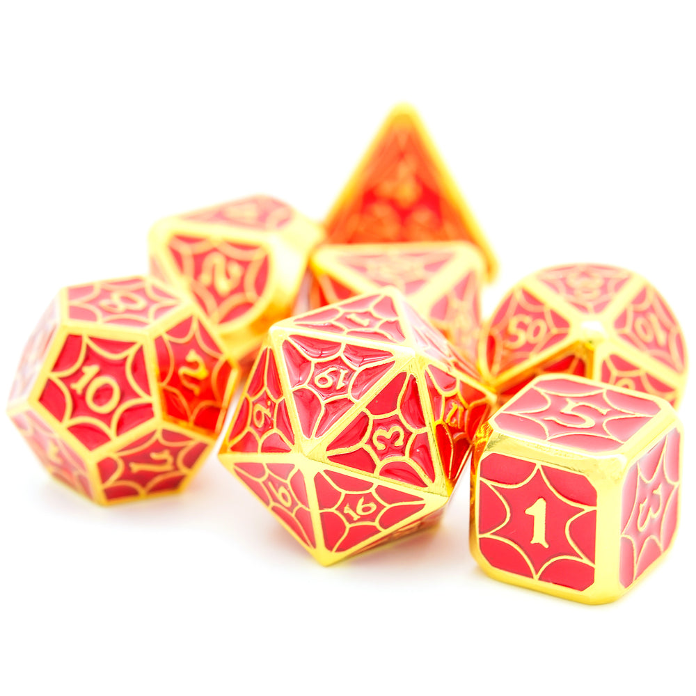 Red and gold metal dice, d20, d6 and d12 in the front with rest of the 7 piece dice set in the back