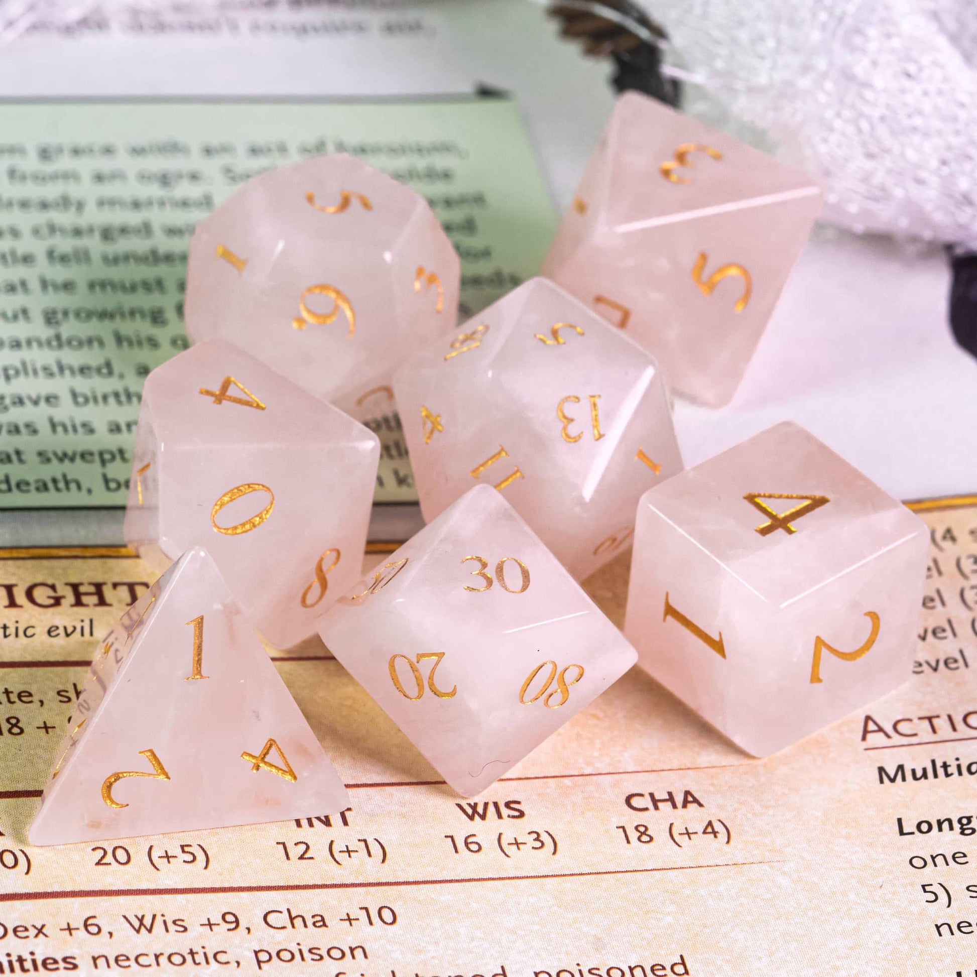 light pink 7 piece stone dice set sitting on monster manual page