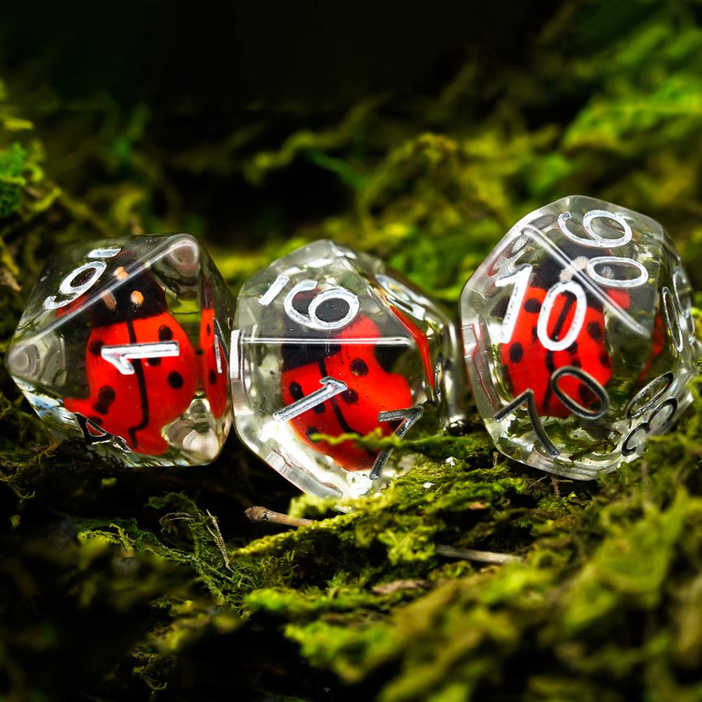 d8 d10 and percentage dice with ladybugs in clear resin, mossy woodland background