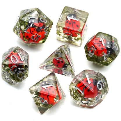 Clean flat lay of all 7 dice from Transparent Ladybug set with red ladybugs inside resin